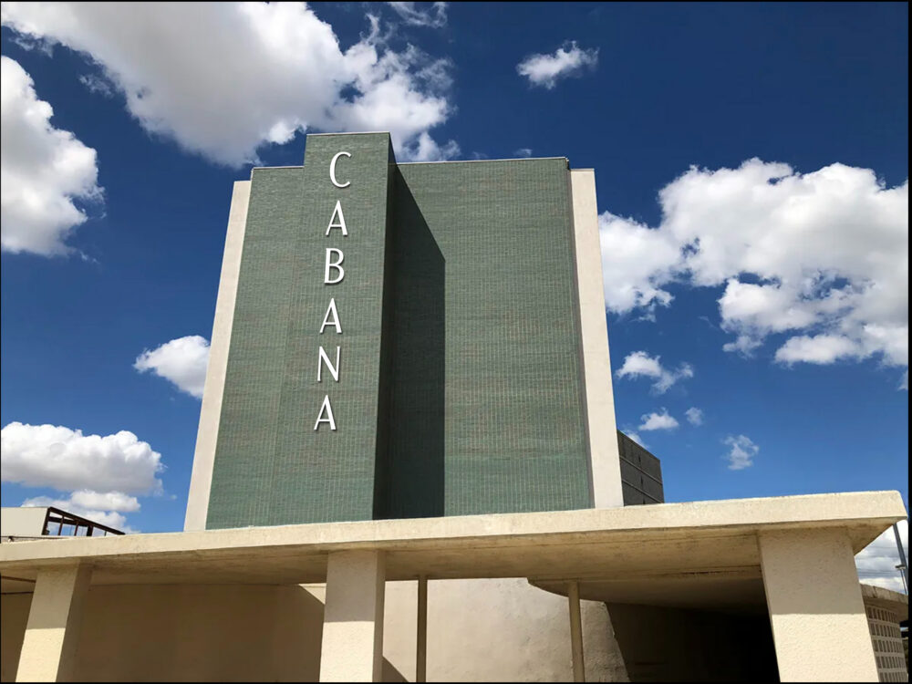 A tall, historic building with green tiles and the word "CABANA" in vertical white letters, set against a blue sky with scattered clouds—a standout among Dallas Apartments.