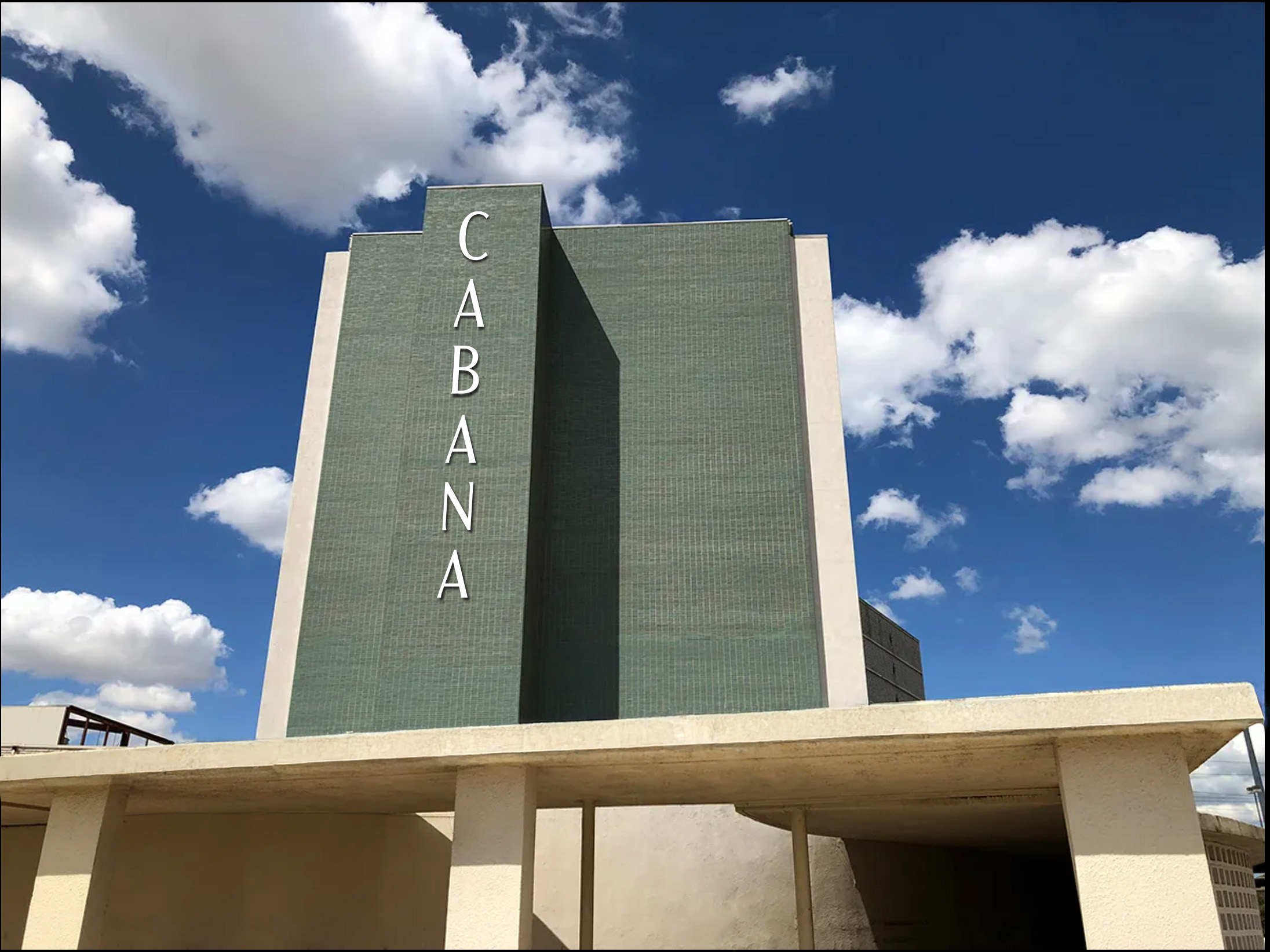 A tall, historic building with green tiles and the word "CABANA" in vertical white letters, set against a blue sky with scattered clouds—a standout among Dallas Apartments.
